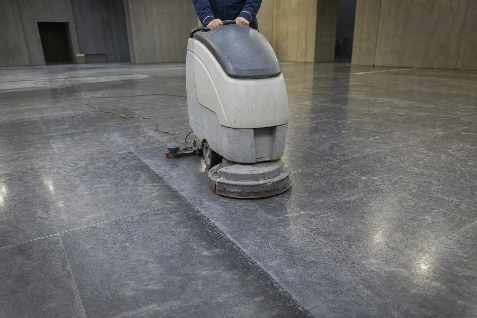 Walk-behind auto scrubber deep cleaning a large stone floor